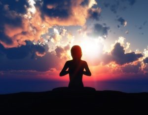 Woman meditating with sunset background