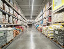 Image showing the inside of a warehouse with shelves on both sides of a walkway. The shelves are all stocked with building materials.