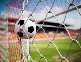 Close up image of a football going into the back of a net