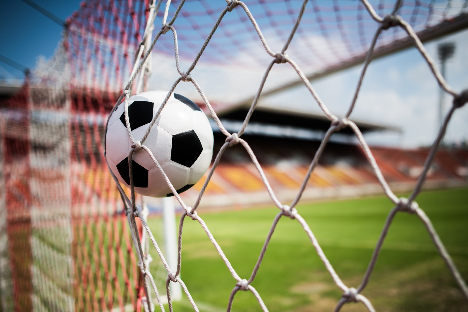 Close up image of a football going into the back of a net