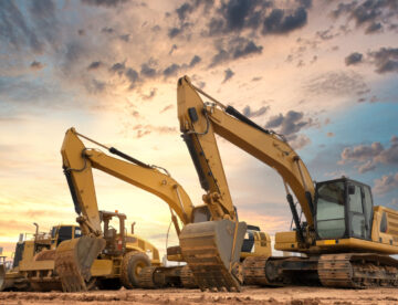 Image of two excavators on a construction site with a dramatic sky in the background