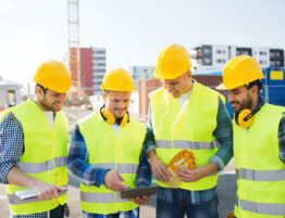 Group of four construction workers on site looking at a tablet during a training session.
