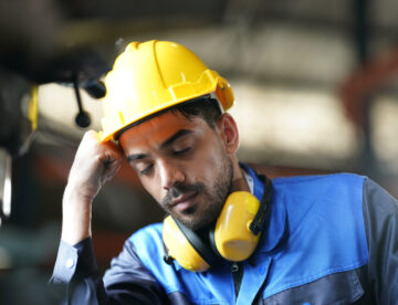 Image of a construction worker with his eyes closed and leaning his head on one hand