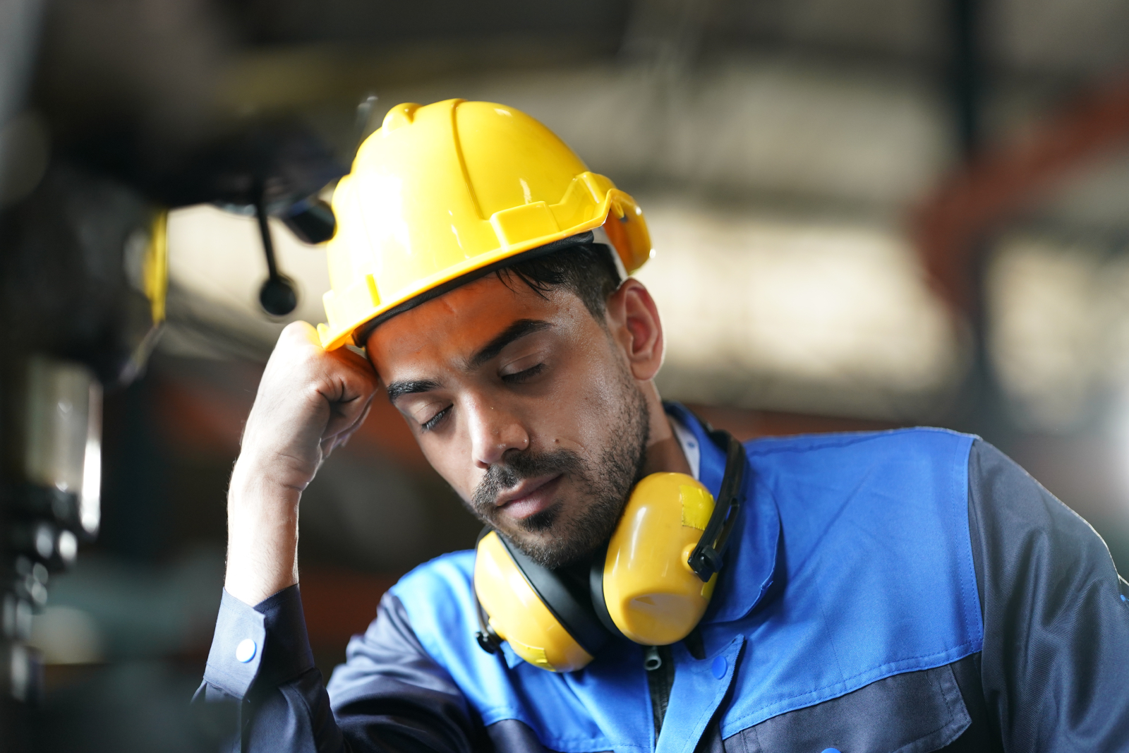 Image of a construction worker with his eyes closed and leaning his head on one hand