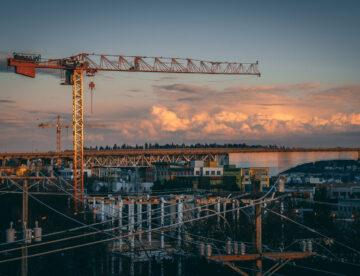 Aerial image showing a construction site with several buildings and a crane set against a darkening evening sky