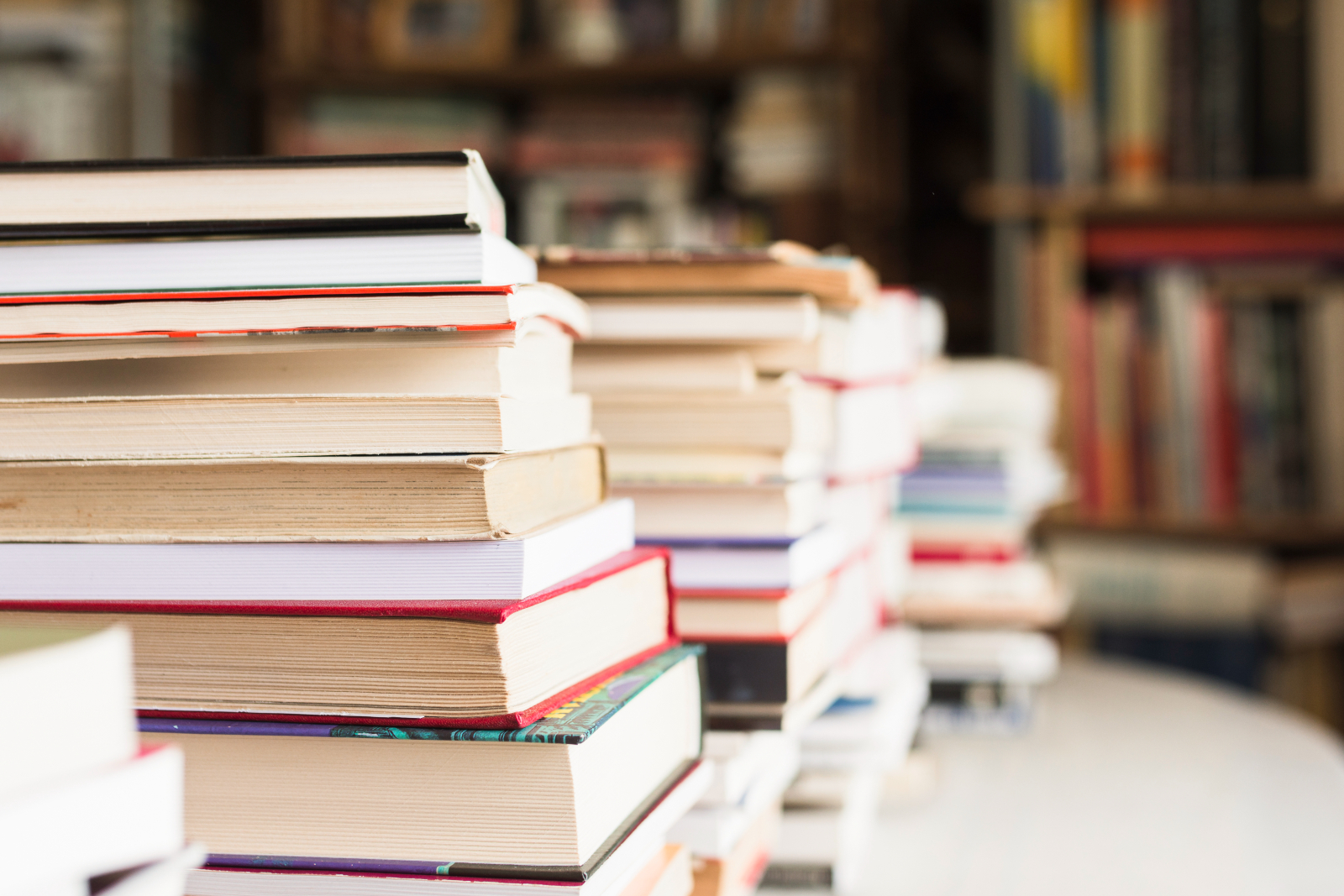 Image showing piles of books set out on a table with a blurred book store background.