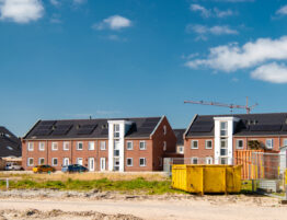 Housing development site featuring cosntruction machinery and set against a bright blue sky