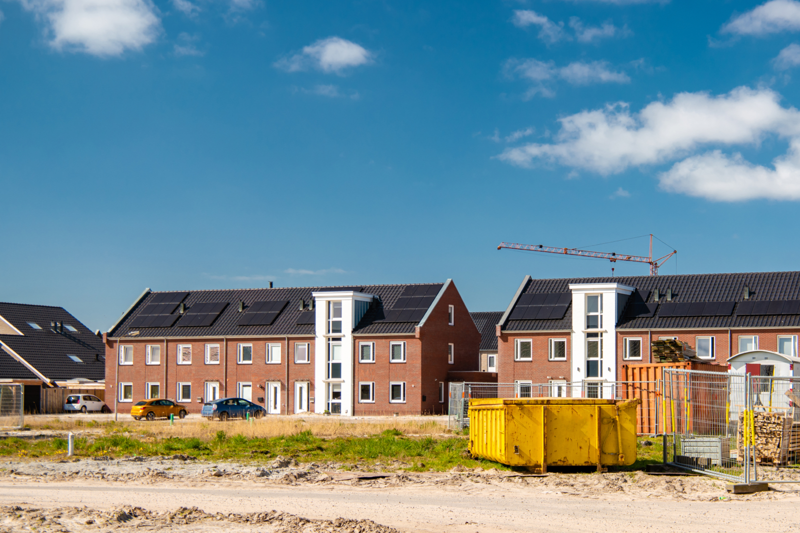 Housing development site featuring cosntruction machinery and set against a bright blue sky