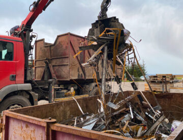 An excavator dropping waste into a skip on a construction site
