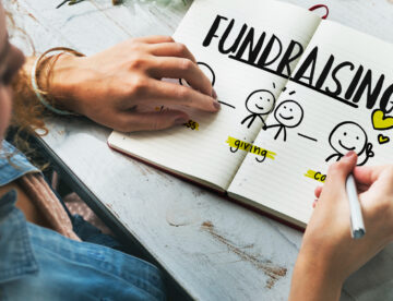 Close up of a woman working on a fundraising plan in a notebook