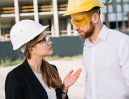 A man and a woman on a construction site talking face-to-face