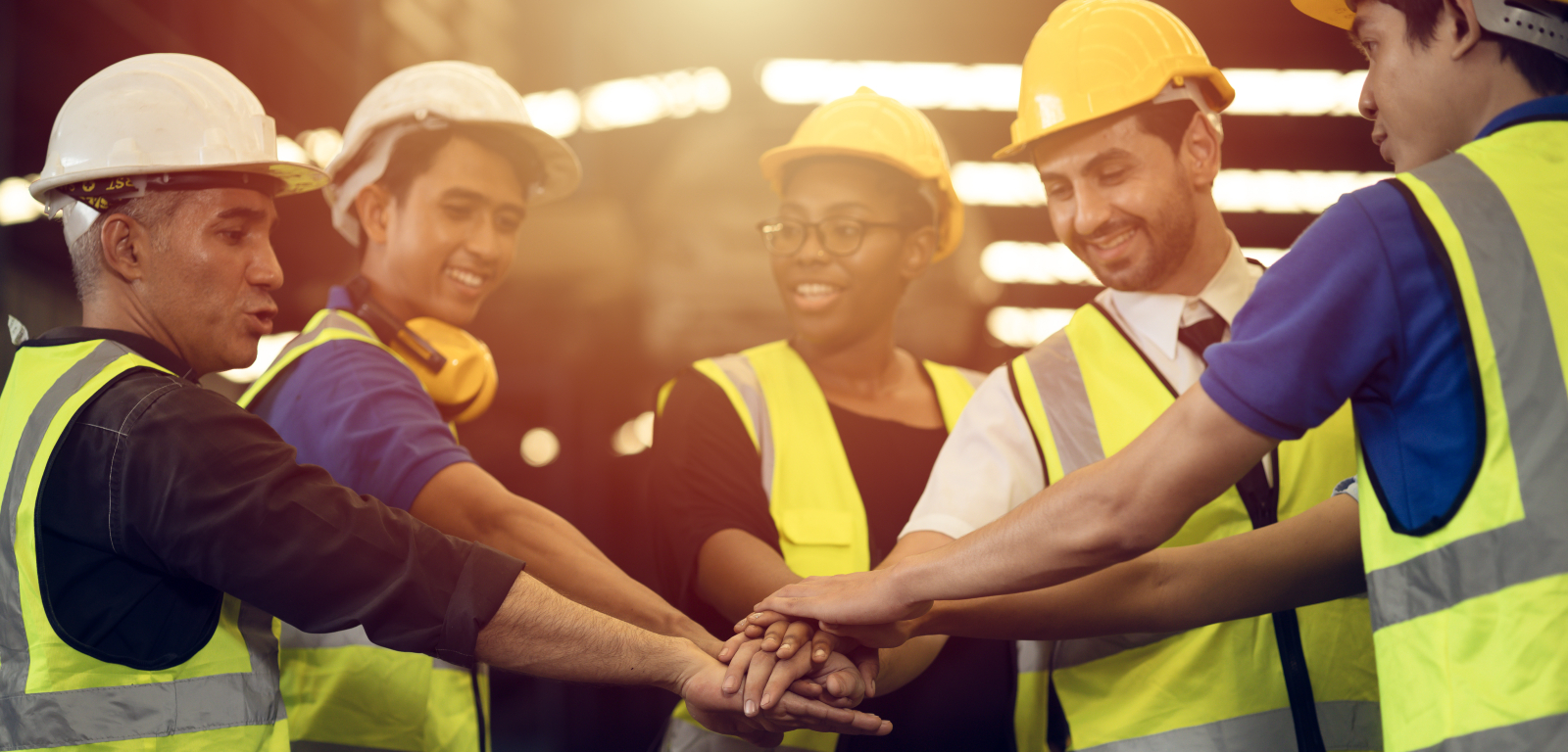 Diverse group of construction workers with hands together in the centre of the image