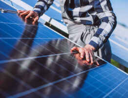Close up of rooftop solar panels with a worker on the project partially visible
