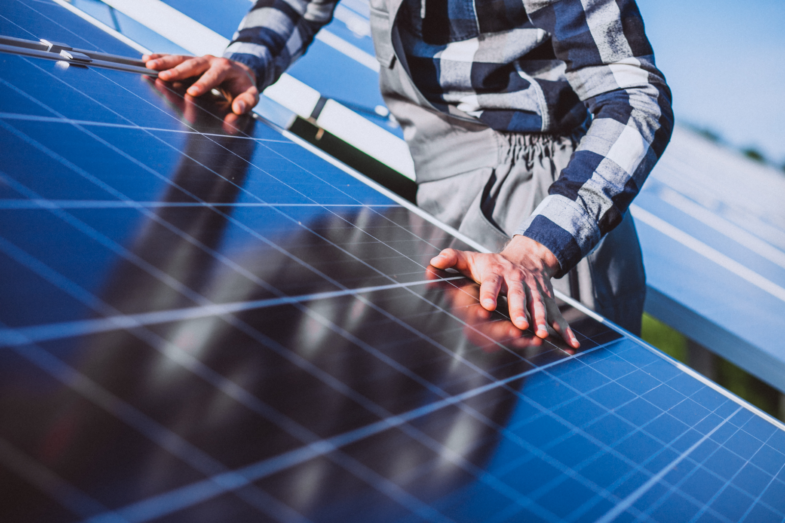 Close up of rooftop solar panels with a worker on the project partially visible