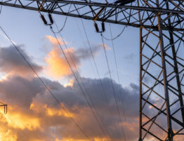 Electricity pylon set against a sky with clouds tinged by the sunset