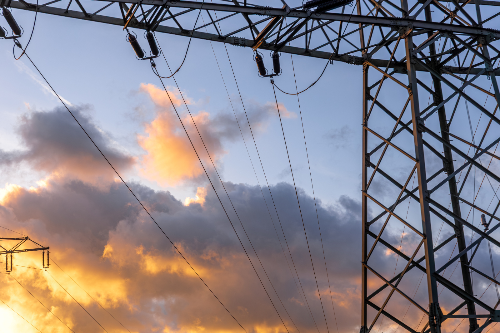 Electricity pylon set against a sky with clouds tinged by the sunset