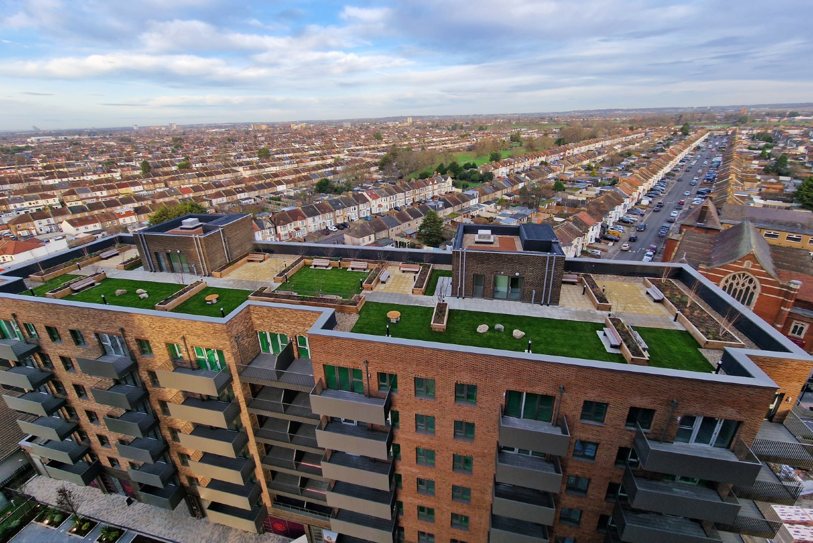 Aerial view of a roofing project (*featuring green roofing and other forms of flat-roofing) with a city background