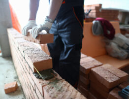 Close up of someone laying bricks in a straight line