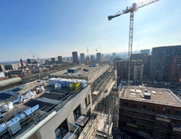 Aerial view of an apartment block under construction with the London skyline and cranes in the background