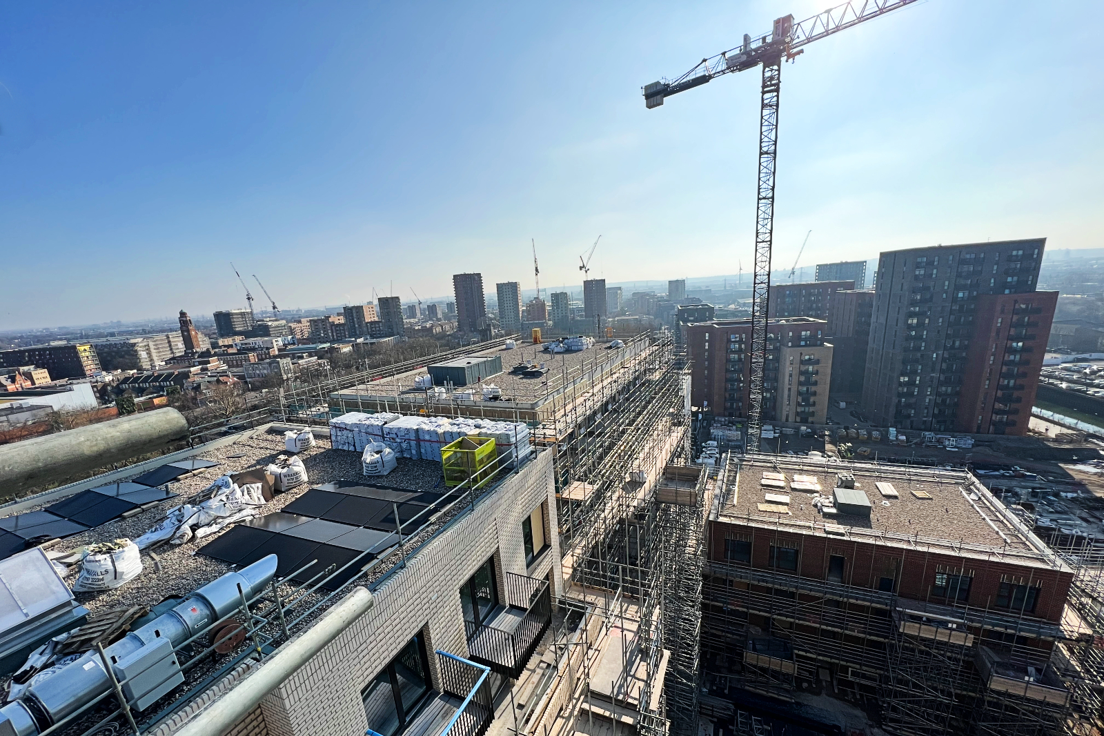 Aerial view of an apartment block under construction with the London skyline and cranes in the background