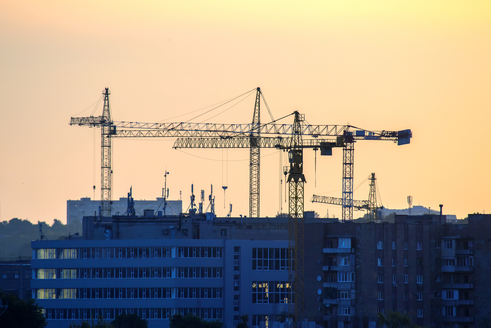Construction site silhouetted against an early evening, darkening sky