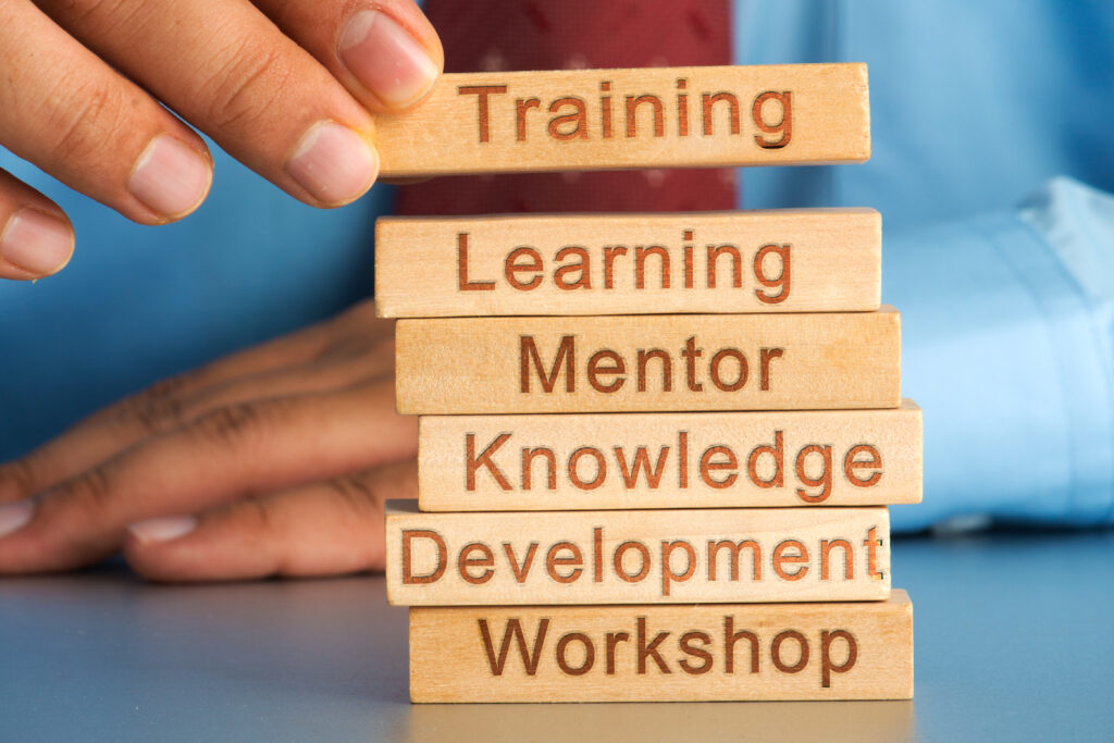 Close up of someone placing small wooden blocks into a tower shape with each block featuring words like training, learning and development