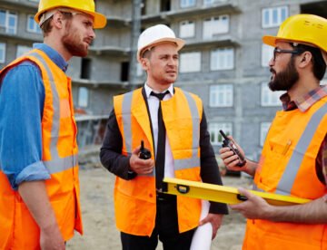 Three construction workers on site, talking to each other face-to-face, representing effective communication