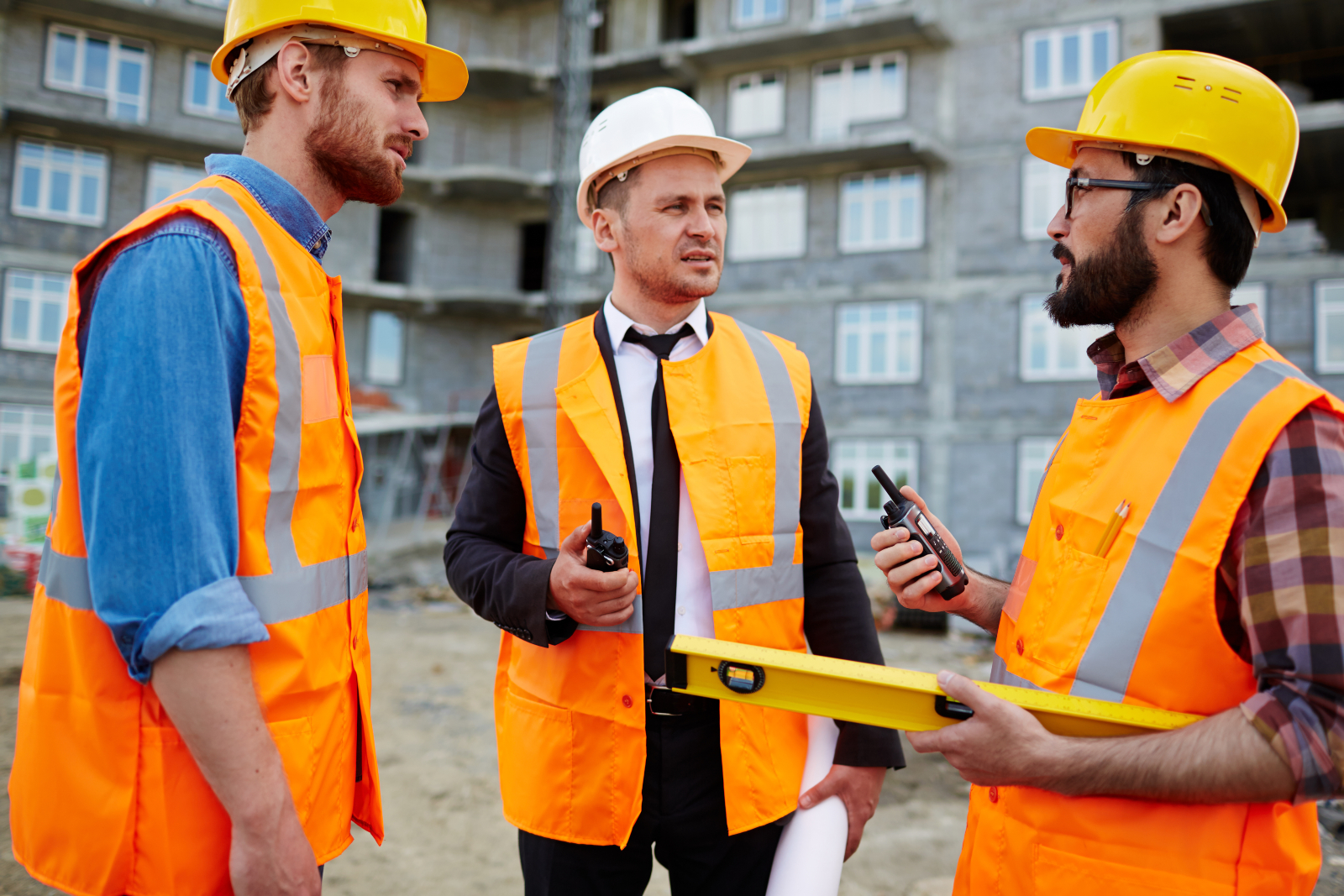 Three construction workers on site, talking to each other face-to-face, representing effective communication