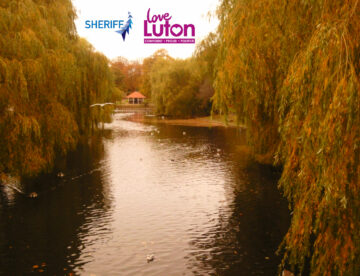 Wardown park in Luton showing the River Lea and a bronze hue. Logos for Sheriff Construction and Love Luton also feature