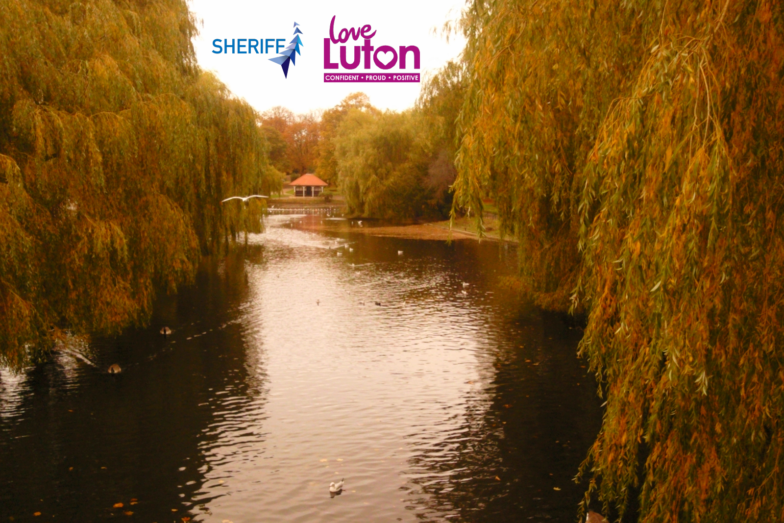 Wardown park in Luton showing the River Lea and a bronze hue. Logos for Sheriff Construction and Love Luton also feature