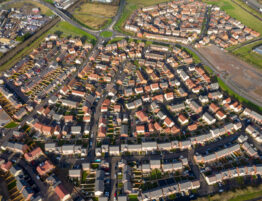 Aerial shot of a housing development in England with roads and a roundabout clearly visible. Some signs of new development appear at the edges of the image.