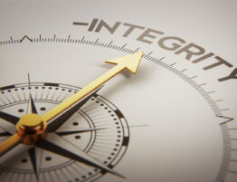 Close up of a compass with a gold arrow pointing towards the word 'integrity'.