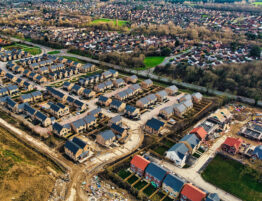 Aerial photo of a housing development, partially completed with views of the wider urban environment in the background.