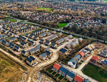 Aerial photo of a housing development, partially completed with views of the wider urban environment in the background.